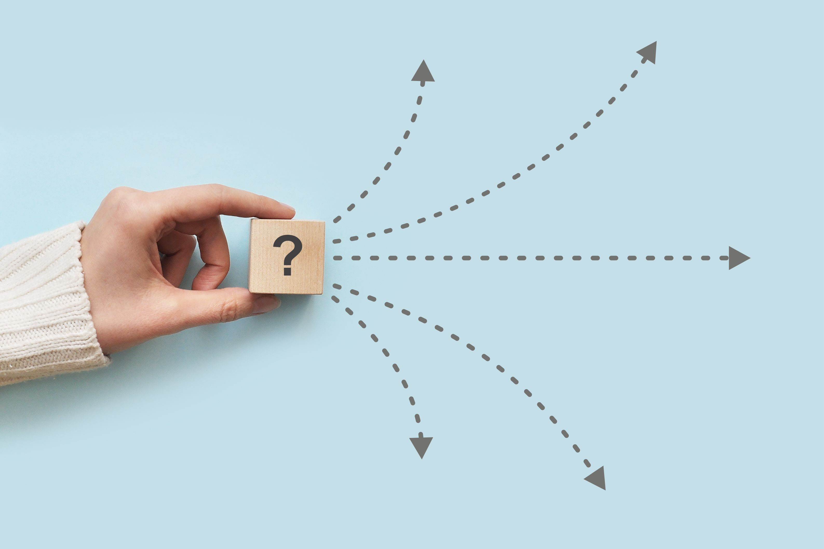 Hand hält Würfel mit Fragezeichensymbol